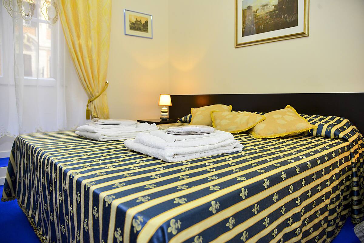 A neatly made bed with a striped bedspread, a bedside lamp, and a window with curtains.
