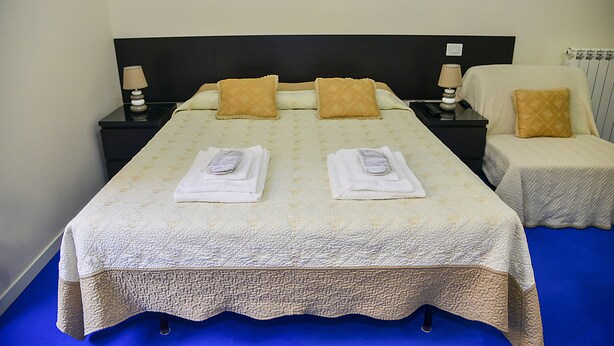 Una habitación de hotel con una cama grande, dos mesitas de noche y una silla.