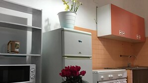 Una cocina con microondas, refrigerador, estufa y una mesa con un florero.
