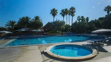 Alberca al aire libre, sombrillas en la alberca y camastros