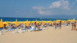 A beach with rows of sun loungers and yellow umbrellas, people sunbathing and walking on the sand. - TH Pizzo Calabro - Porto Ada Village (Pizzo)