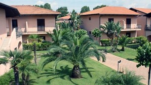 A courtyard with palm trees and a building with balconies. - TH Pizzo Calabro - Porto Ada Village (Pizzo)