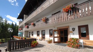 Un hôtel doté d’une cour pavée de pierres, de balcons en bois ornés de jardinières et d’un banc en bois.
