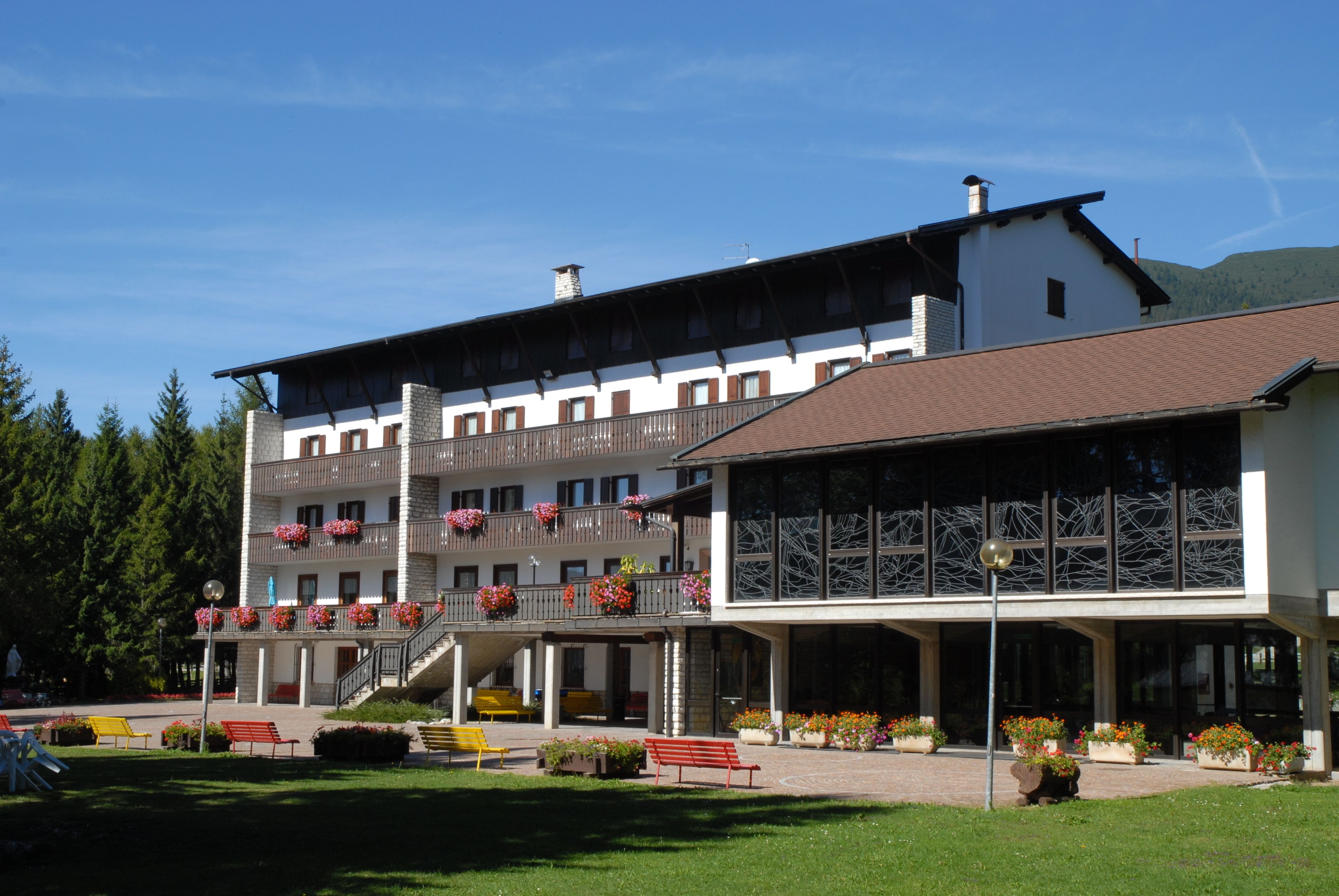 A multi-story hotel with balconies, outdoor seating, and a landscaped garden.