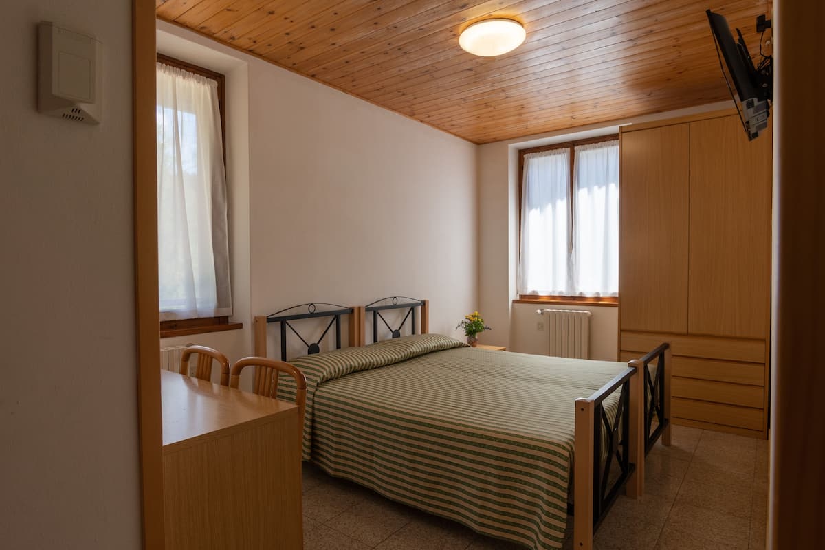 Ein Schlafzimmer mit Bett, einem Holztisch, einem Stuhl und einem Fenster mit Vorhängen.