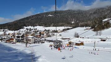 Une station de ski enneigée, avec des bâtiments, un télésiège et une montagne en toile de fond.