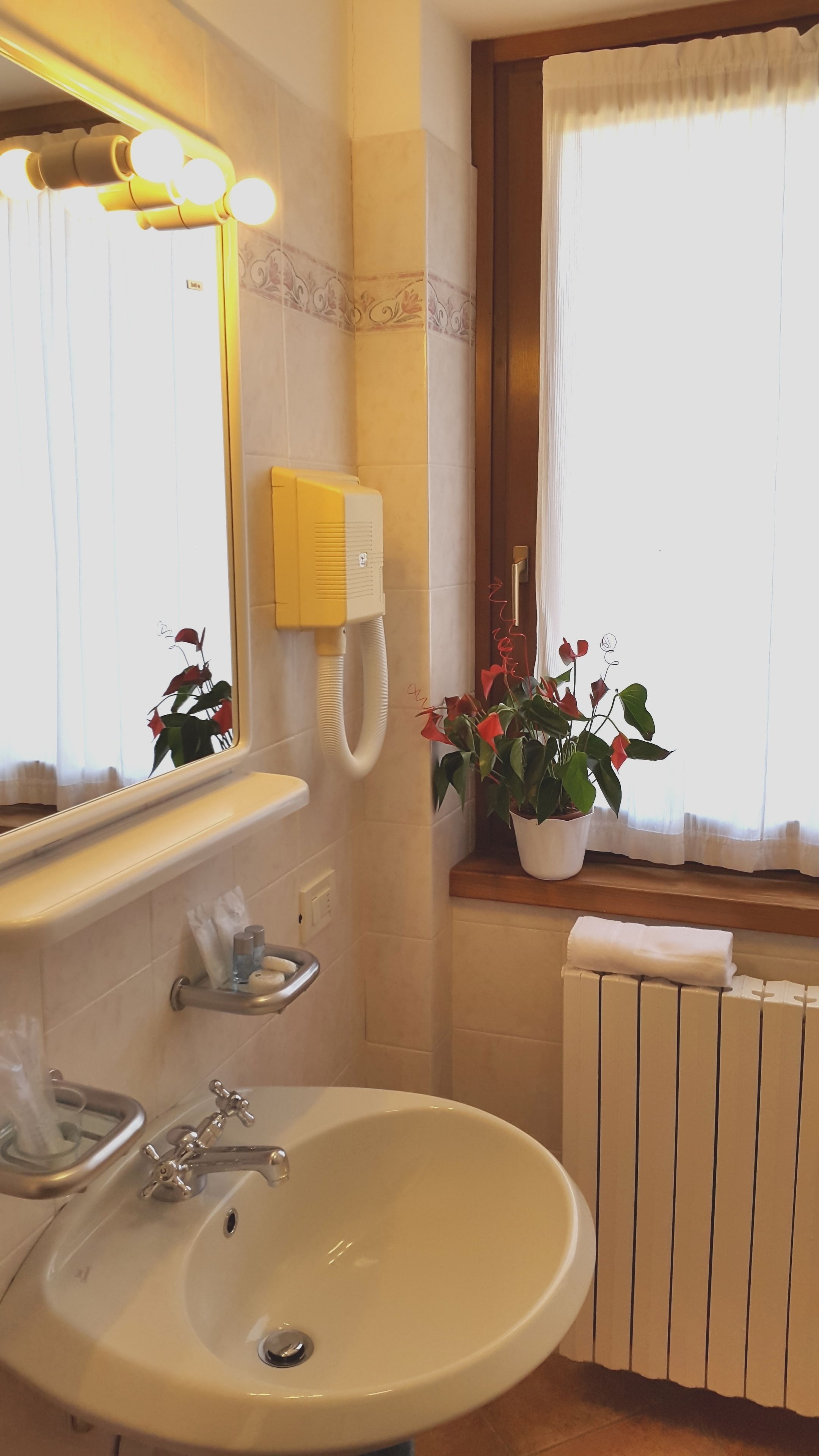 A bathroom with a sink, mirror, and towel rack. There is a window with a view of the outside.
