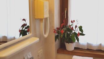 A bathroom with a sink, mirror, and towel rack. There is a window with a view of the outside.