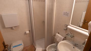 Une salle de bain comprenant des toilettes, une douche, un bidet, un lavabo et un miroir.