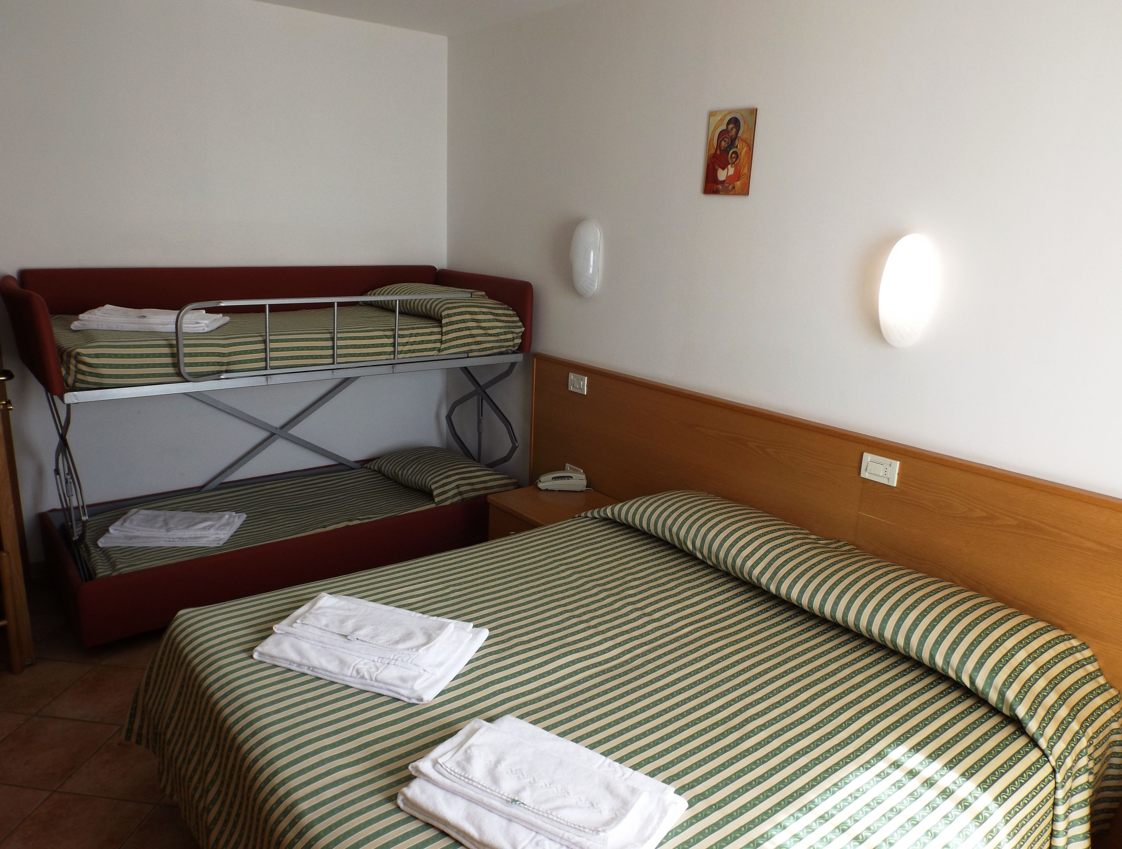 Ein Zimmer mit Etagenbetten, einem Nachttisch, einer Wandleuchte und einem kleinen Gemälde.