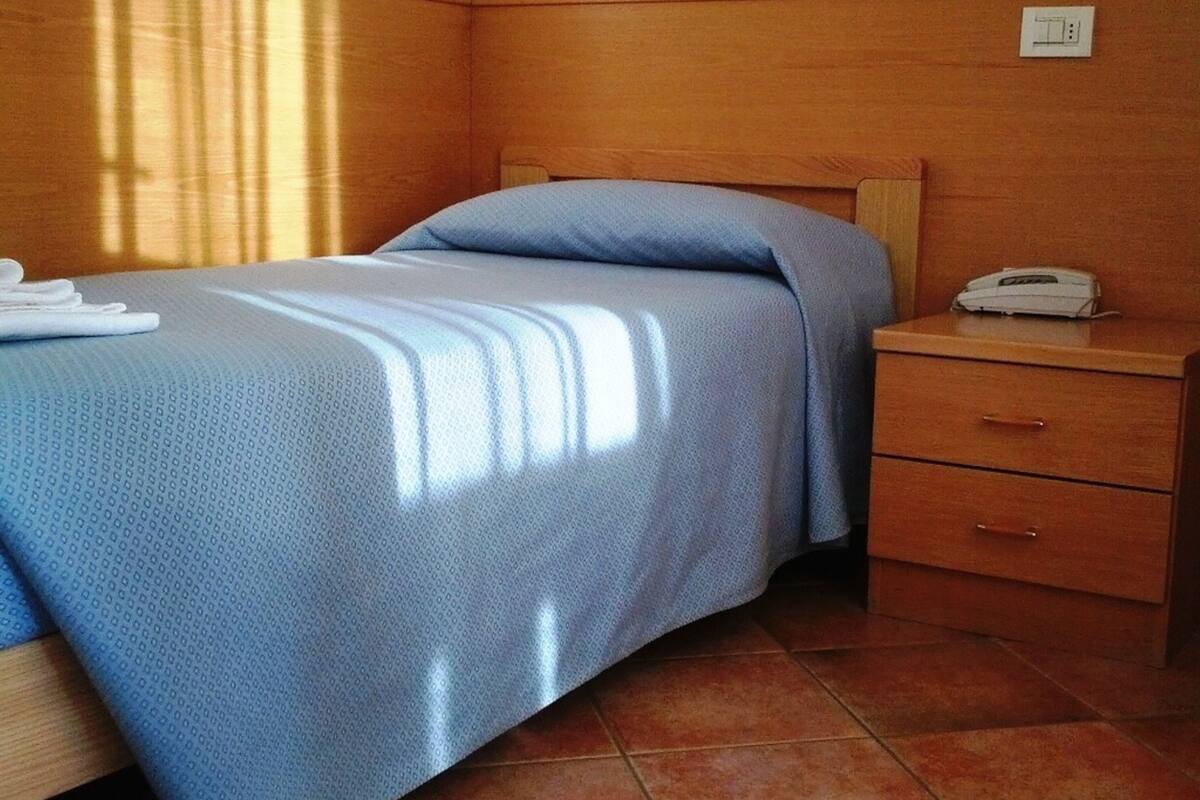 Ein Hotelzimmer mit Bett, Nachttisch, Telefon und Steckdose.