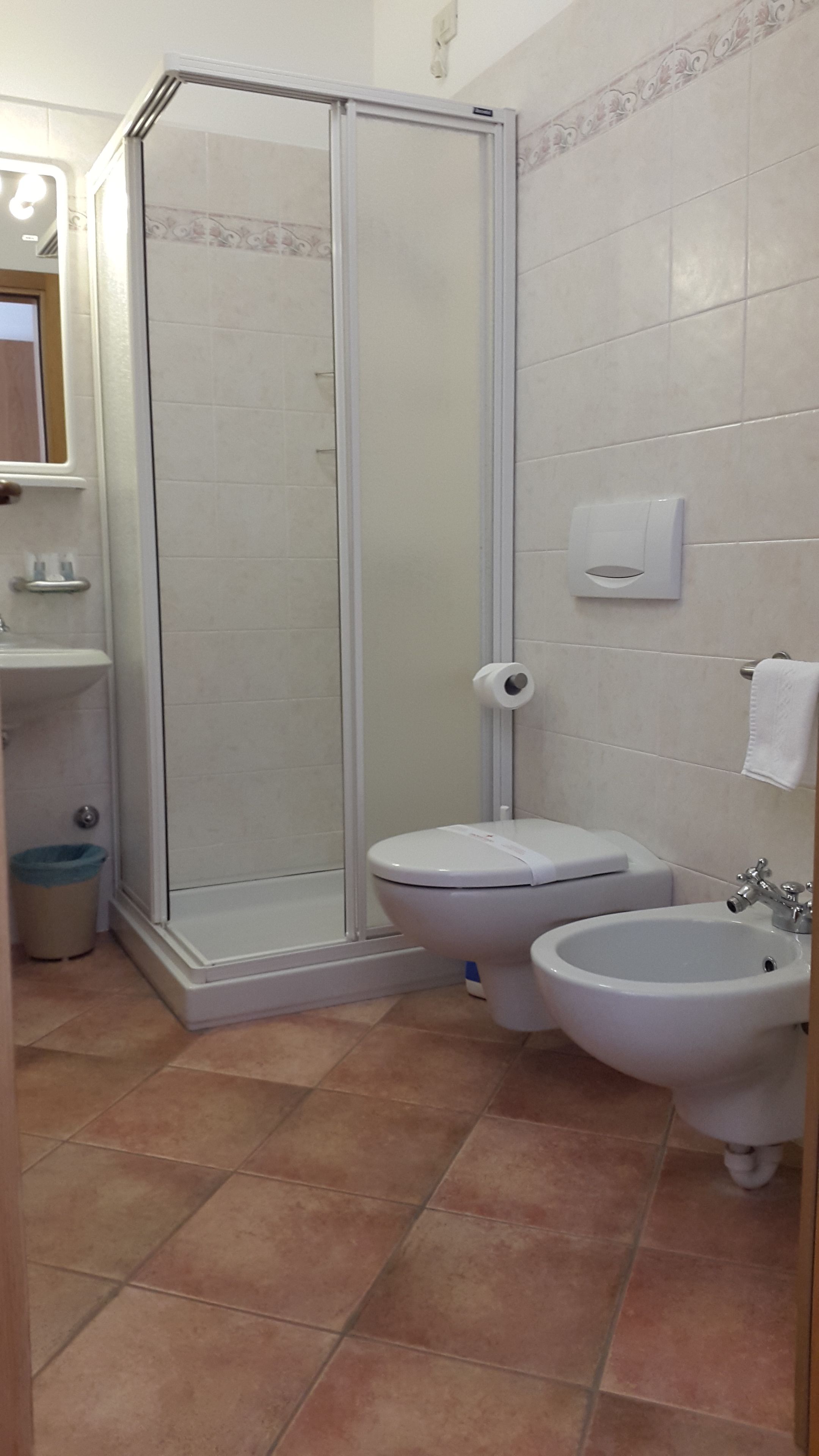 A bathroom with a glass shower enclosure, a toilet, a bidet, and a sink.