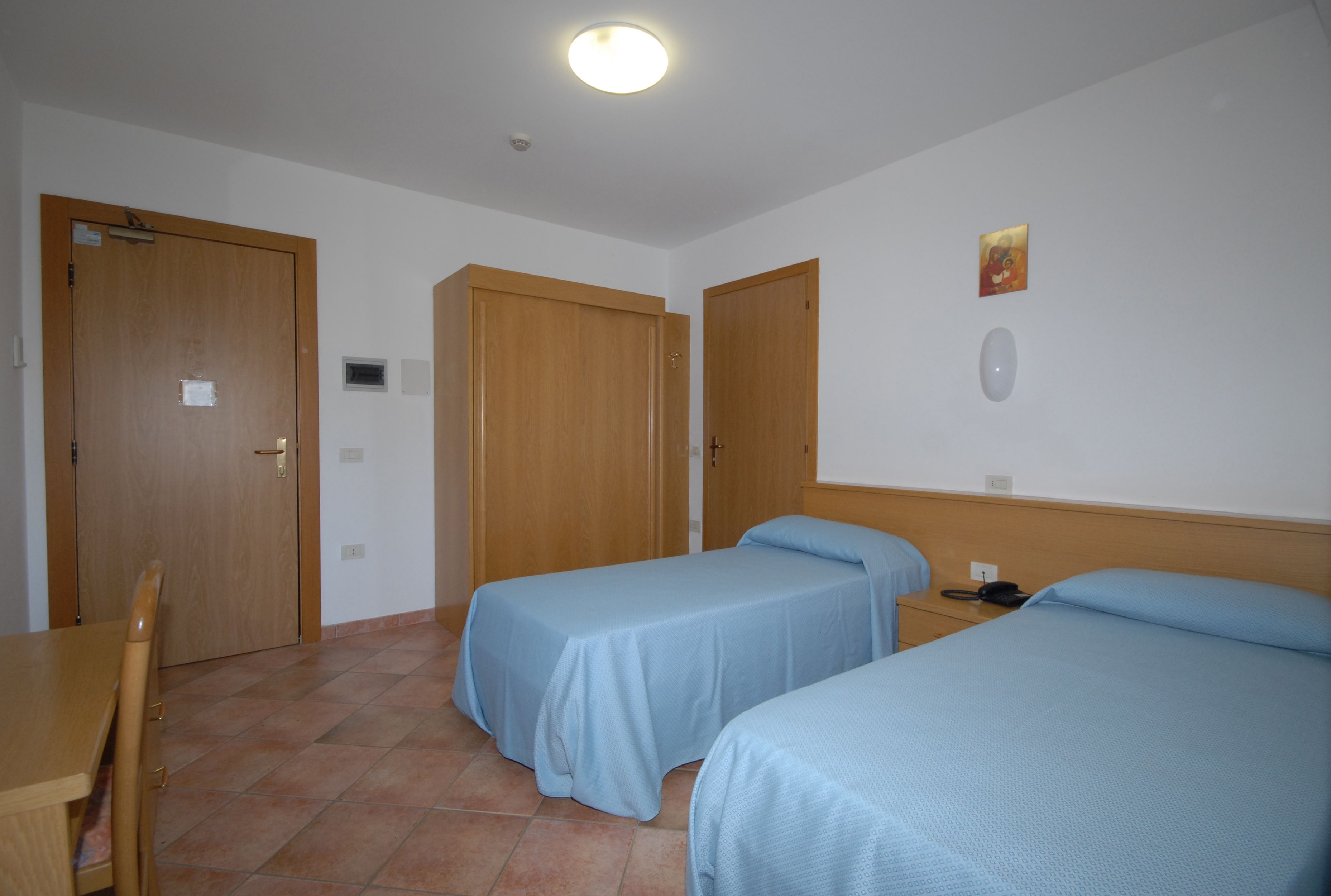 Une chambre d’hôtel avec deux lits simples, un bureau en bois et une chaise.