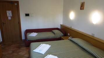 Una camera d'albergo con due letti, una porta in legno, una lampada a parete e un piccolo quadro.