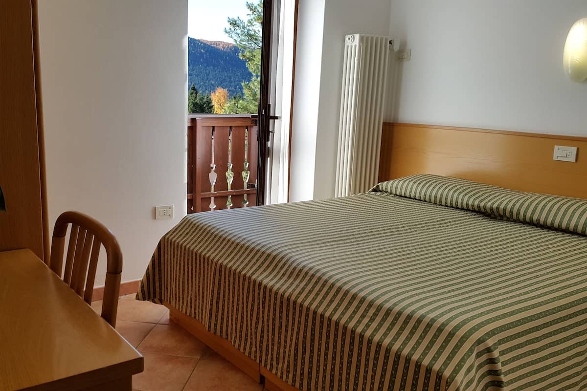 Ein Hotelzimmer mit Bett, Stuhl, Tisch und einer Topfpflanze.
