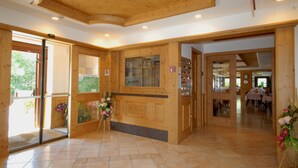 Un espace d’accueil en bois avec une porte vitrée, un comptoir d’accueil et une vue sur la salle à manger.