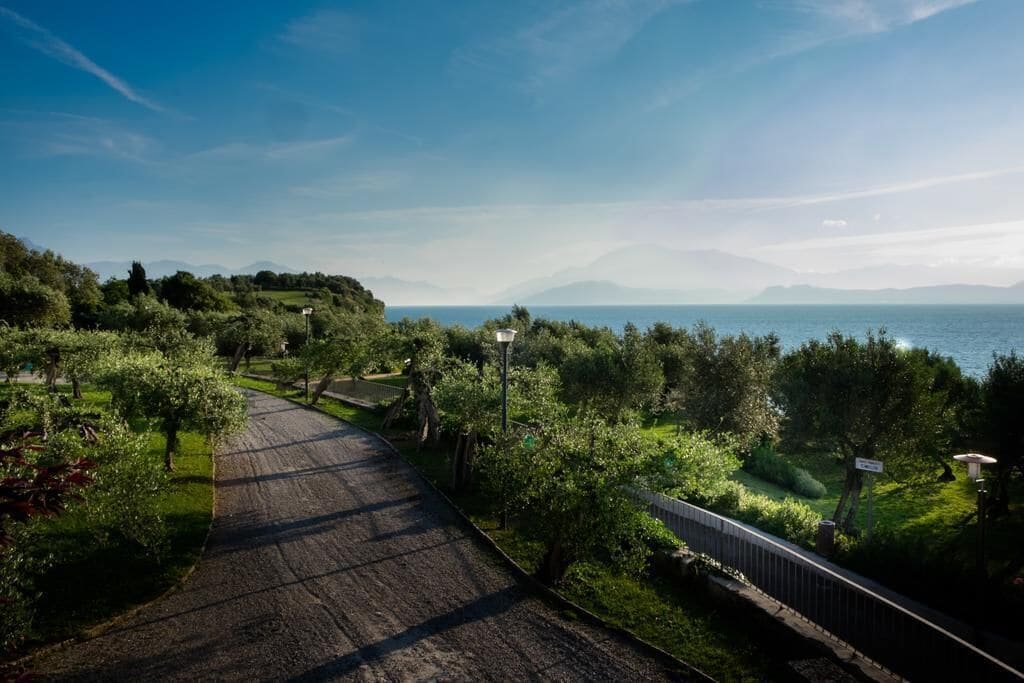 Un camino pavimentado que lleva a un mirador con vistas al mar y montañas a lo lejos.