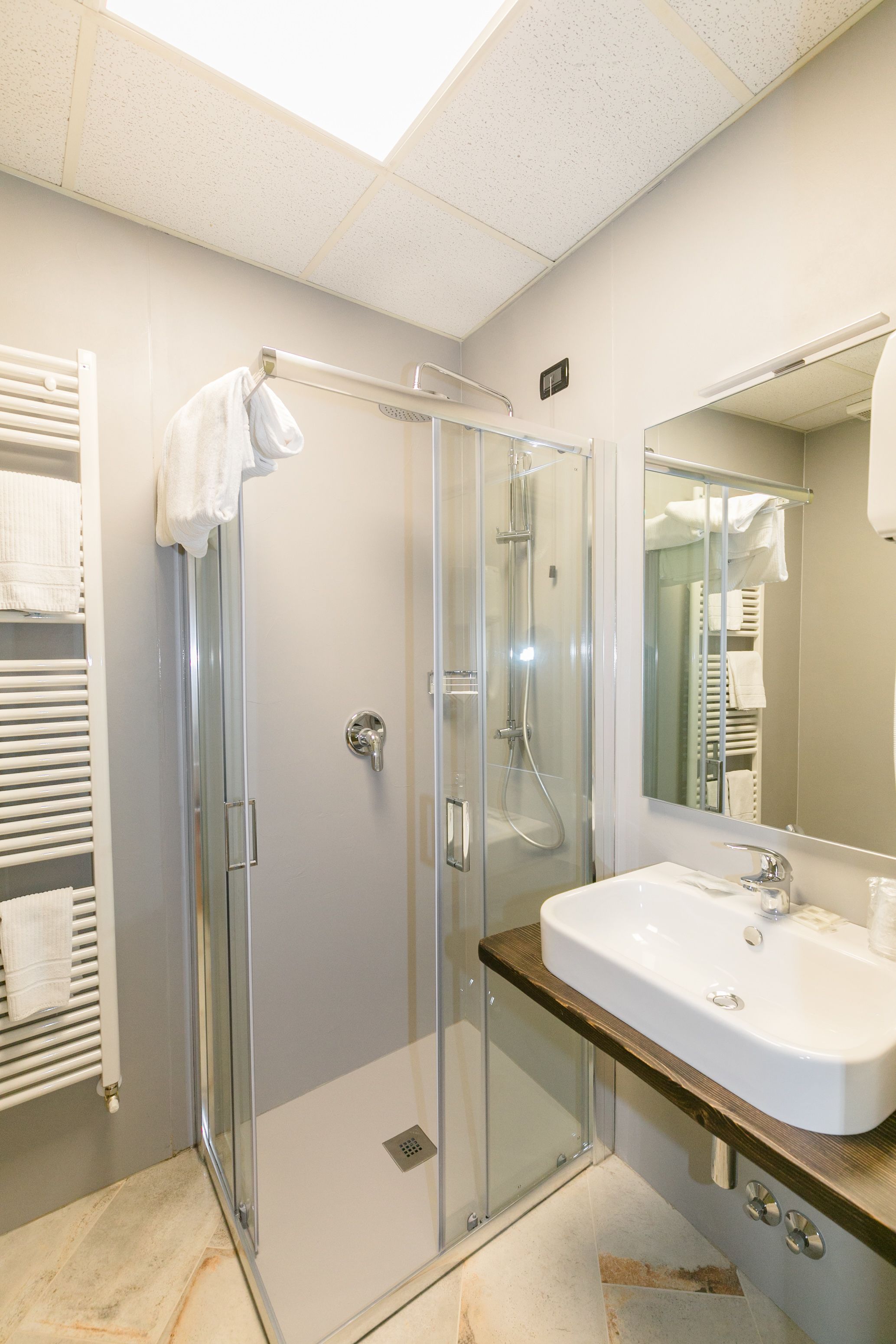 Une salle de bain moderne avec une douche à parois de verre, un lavabo blanc et un grand miroir.