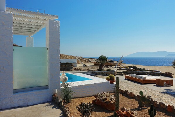 A coastal property with a pool, outdoor seating, and a view of the sea.