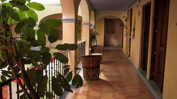 Un pasillo con arcos, una silla y una planta en maceta.
