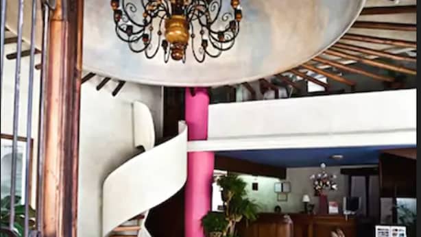 Un hall d’entrée spacieux agrémenté d’un escalier en colimaçon, d’un lustre et d’un comptoir d’accueil.