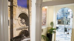 A lobby with a mural of a castle, a large clock, and a potted plant. - Estrela de Arganil (Lisbon)