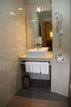 A bathroom with a sink, mirror, towel rack, and a hairdryer on the wall.