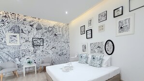 A modern bedroom with a large bed, a small desk, and a chair. The walls are decorated with framed black and white artwork. - Beat Hotel Bangkok (Bangkok)