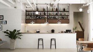 A modern bar area with shelves of bottles, two stools, and a potted plant. - Beat Hotel Bangkok (Bangkok)