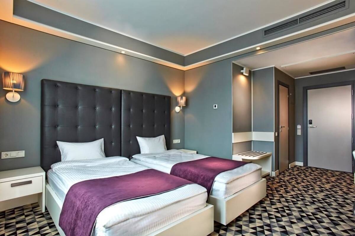 A hotel room with two beds, a checkered floor, and a modern design.