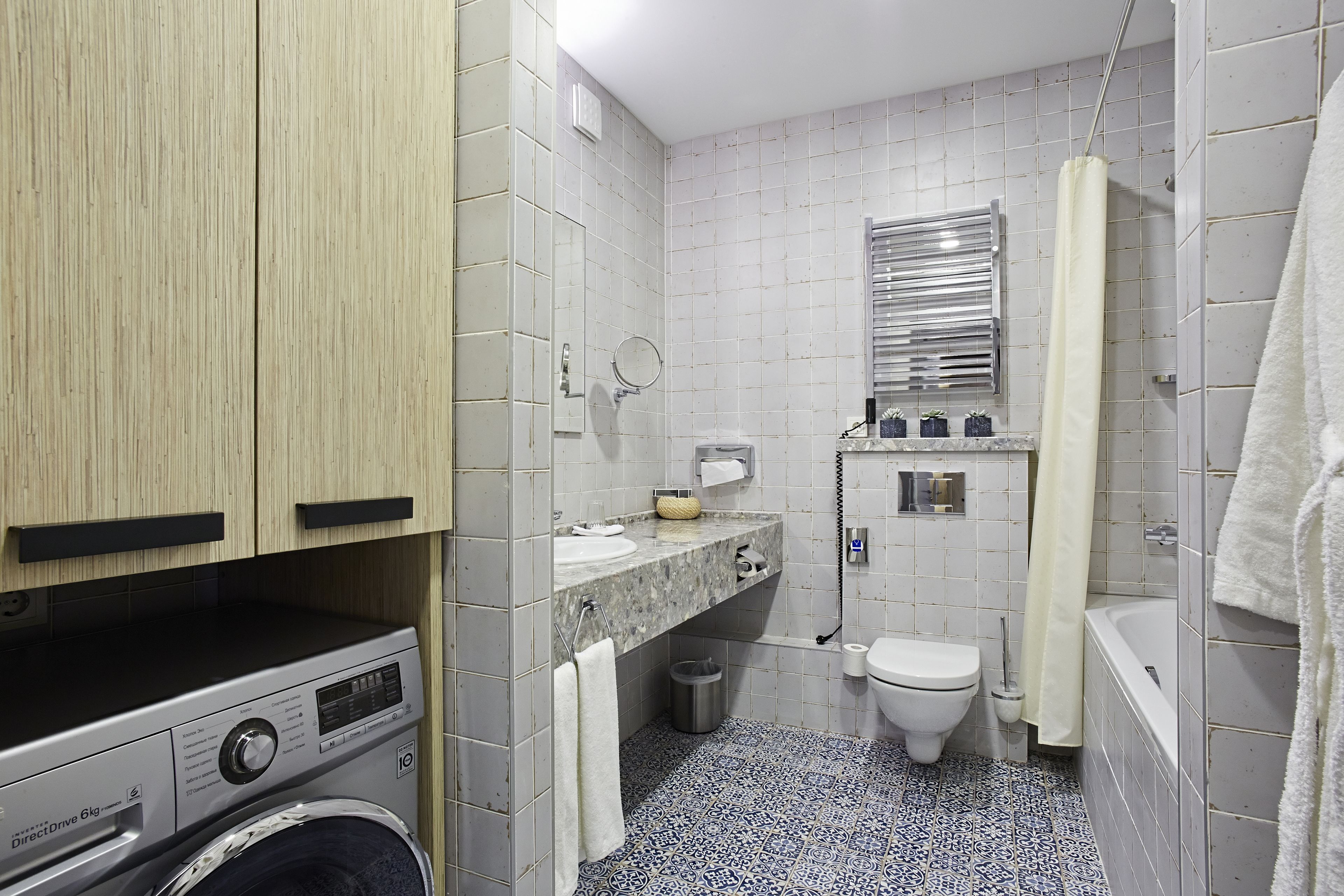 A compact bathroom with a washing machine, toilet, and bathtub.