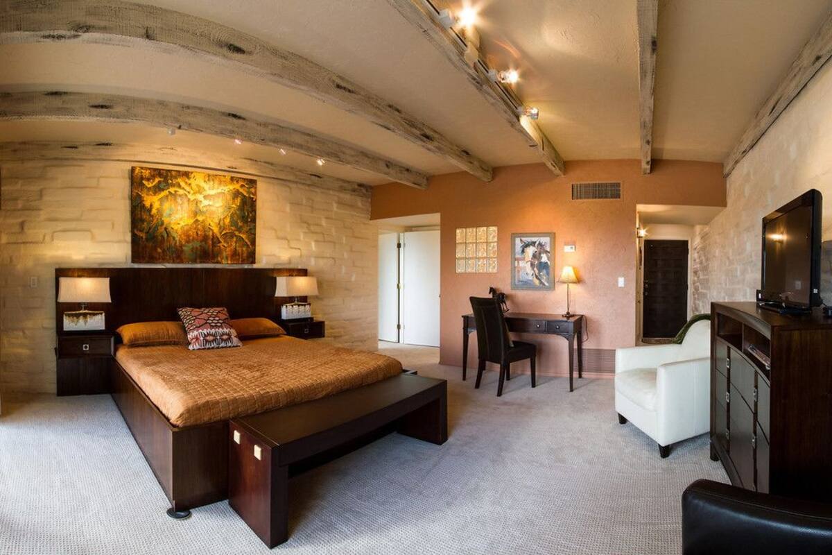 Ein geräumiges Schlafzimmer mit einem großen Bett, einem Schreibtisch und einem Fernseher.