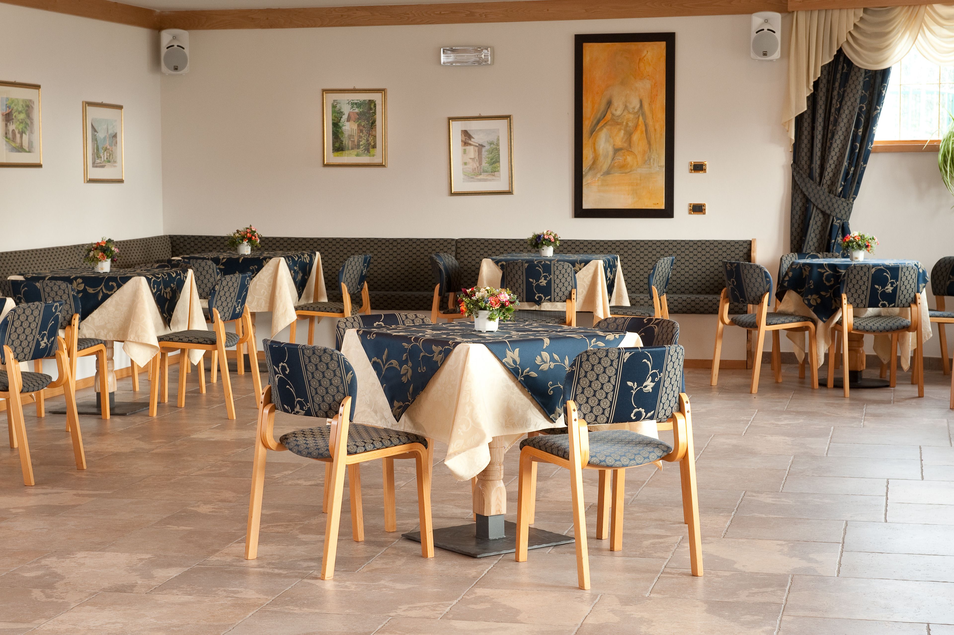 A dining area with round tables, chairs, and framed artwork on the walls.