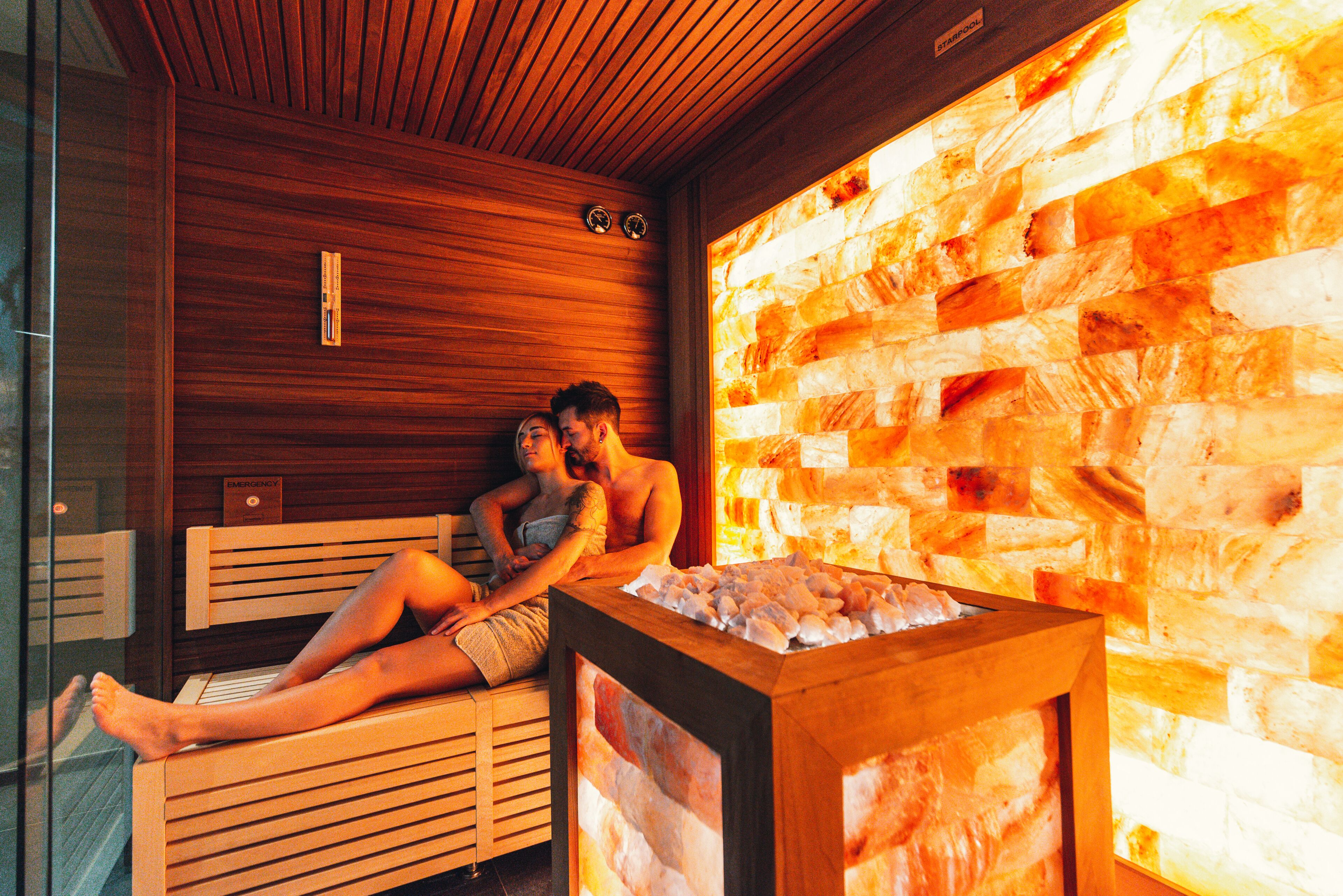 Una sauna con panche in legno e una parete in pietra.