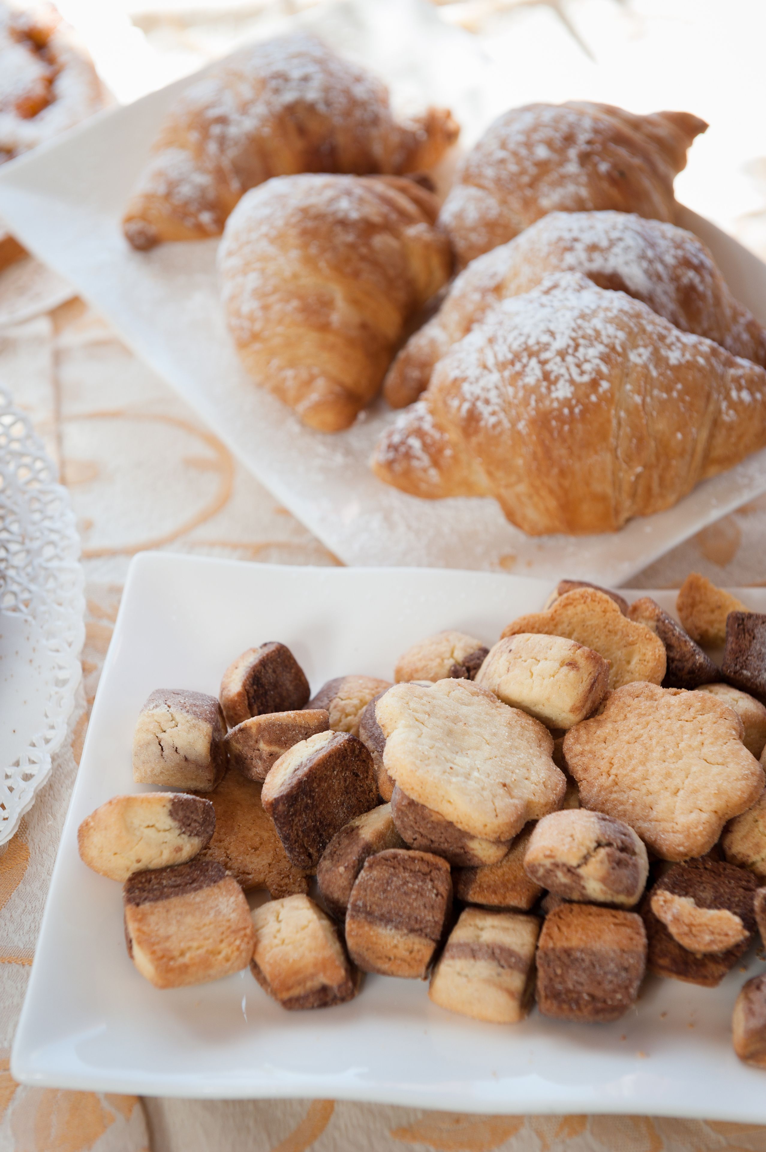 Ein Teller mit verschiedenen Gebäcken, darunter Croissants und kleine Kekse.