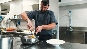 Een kok bereidt eten in een moderne keuken met roestvrijstalen apparatuur en een overzichtelijke, georganiseerde indeling.