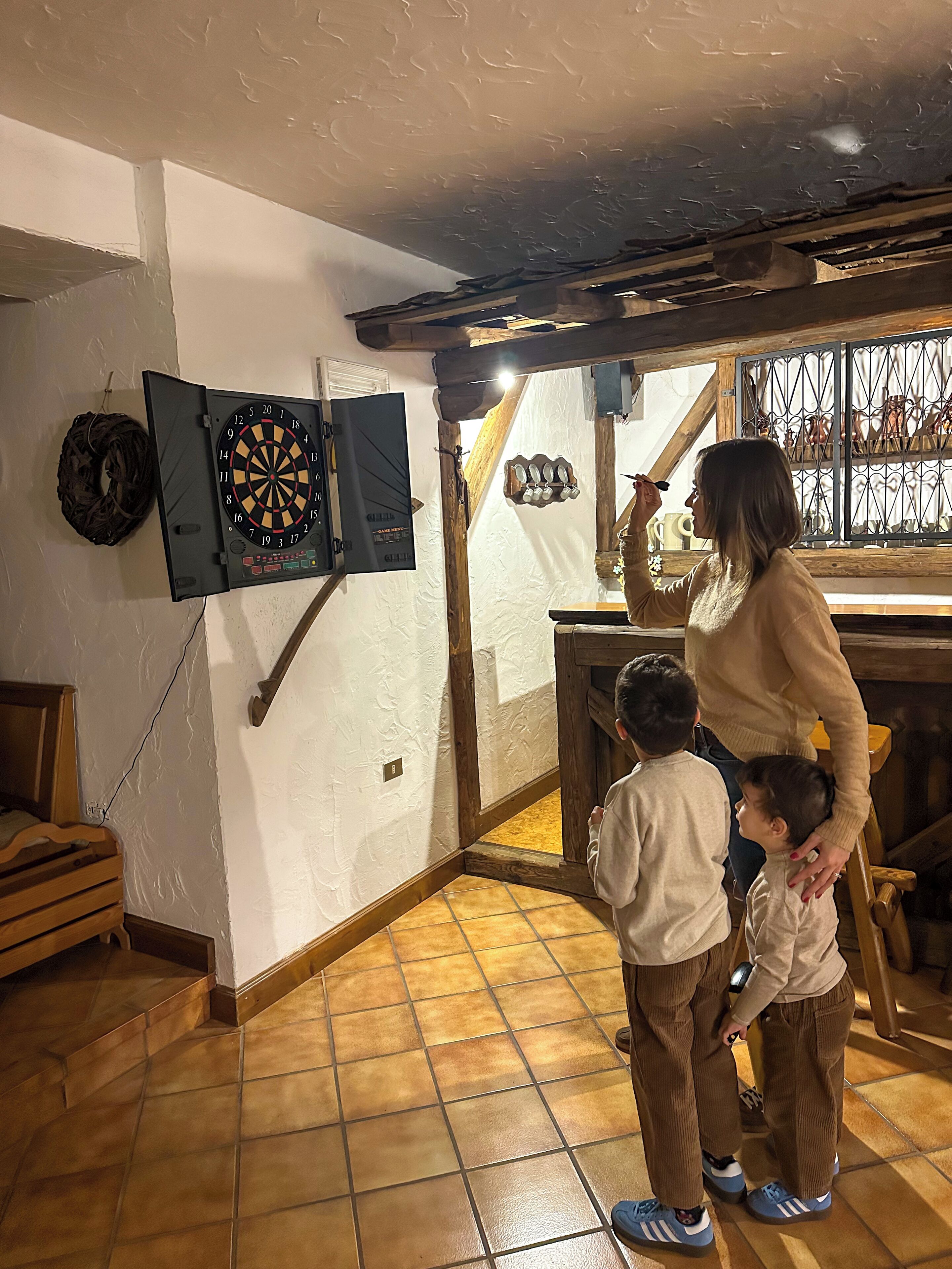 Una habitación con dardos, un banco de madera y una ventana con adornos.