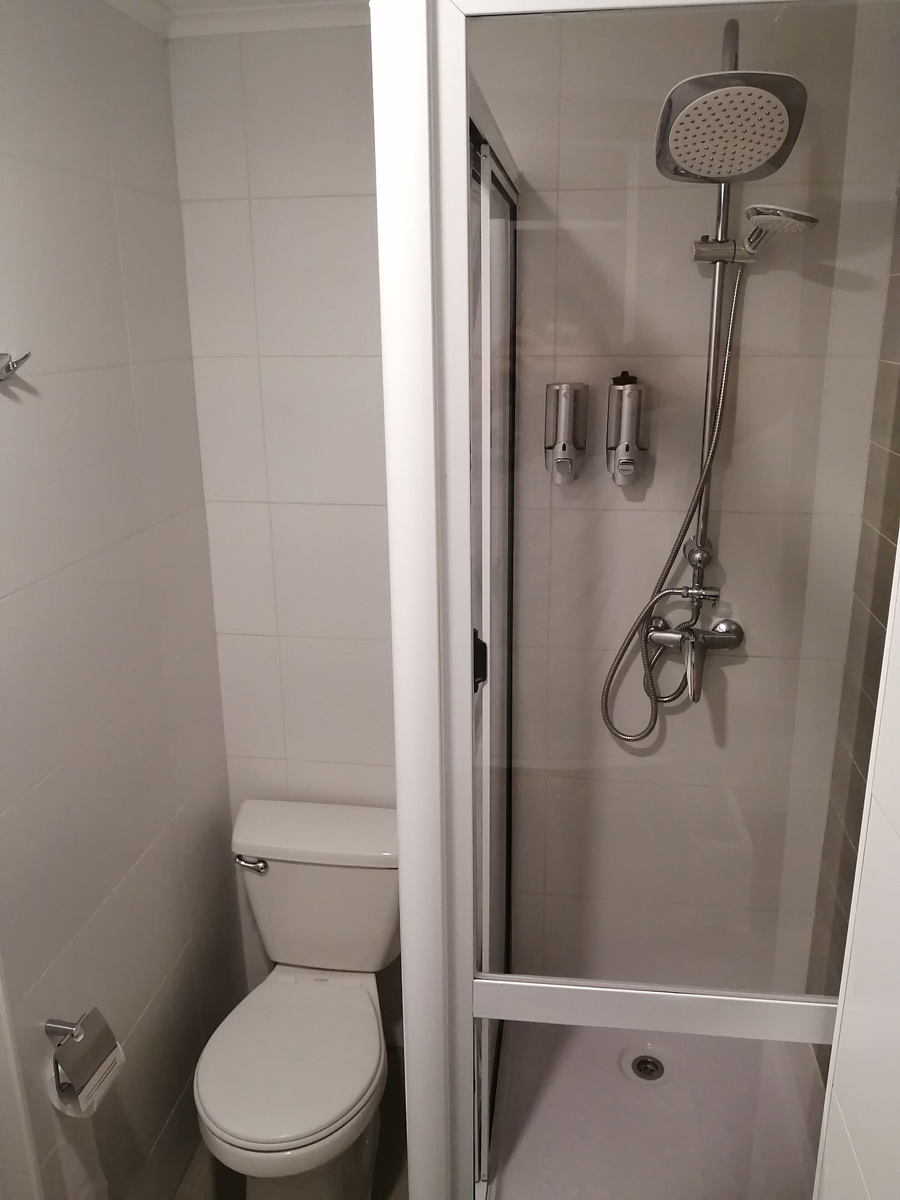Un baño moderno con inodoro, cabina de ducha y puerta de cristal.