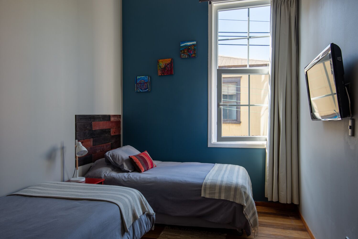Un dormitorio con dos camas, una ventana con cortinas y una obra de arte en la pared.