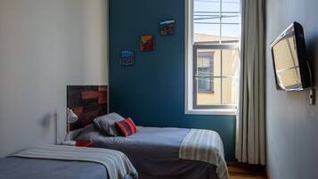 Un dormitorio con dos camas, una ventana con cortinas y una obra de arte en la pared.