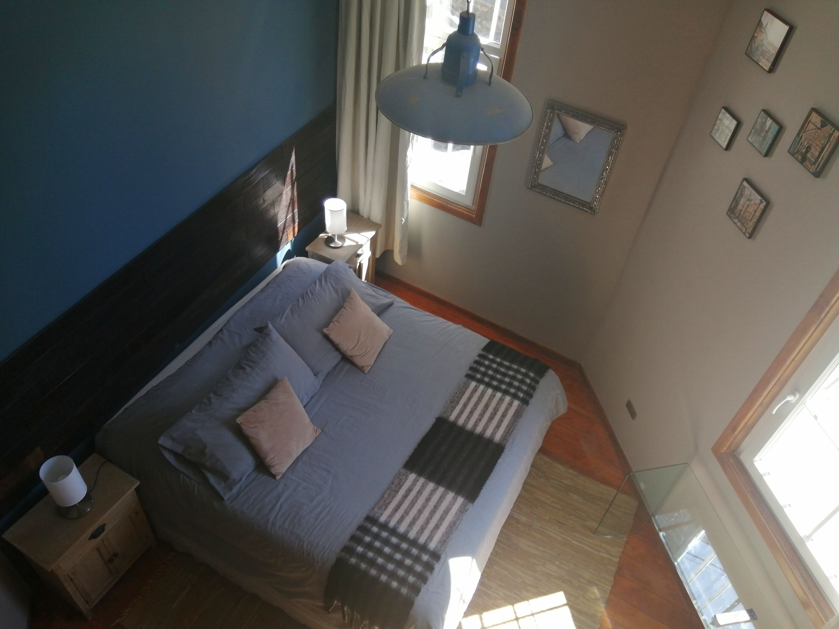 A bedroom with a bed, bedside table, lamp, and a window with curtains.