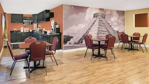Un espace repas doté d’un plancher en bois, de chaises à revêtement rouge et d’une fresque représentant une pyramide.