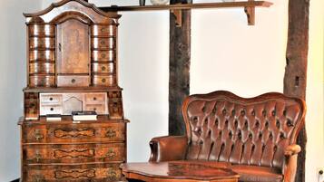 A wooden cabinet with multiple drawers and a cushioned chair with a high backrest.