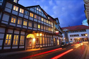 A traditional half-timbered building with illuminated windows and a cobblestone street.