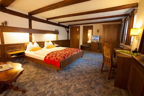 A bedroom with a large bed, wooden headboard, a desk with a lamp, and a television. - Hotel Ritter St. Georg (Braunschweig)