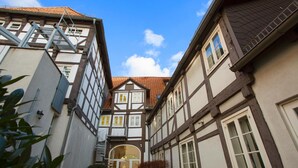 Uma rua estreita com edifícios tradicionais de enxaimel, uma escadaria visível e um céu claro.