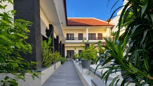 A building with a tiled roof, a covered walkway, and potted plants.