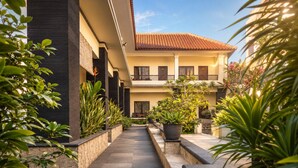 A courtyard with a tiled floor, potted plants, and a building with a tiled roof.