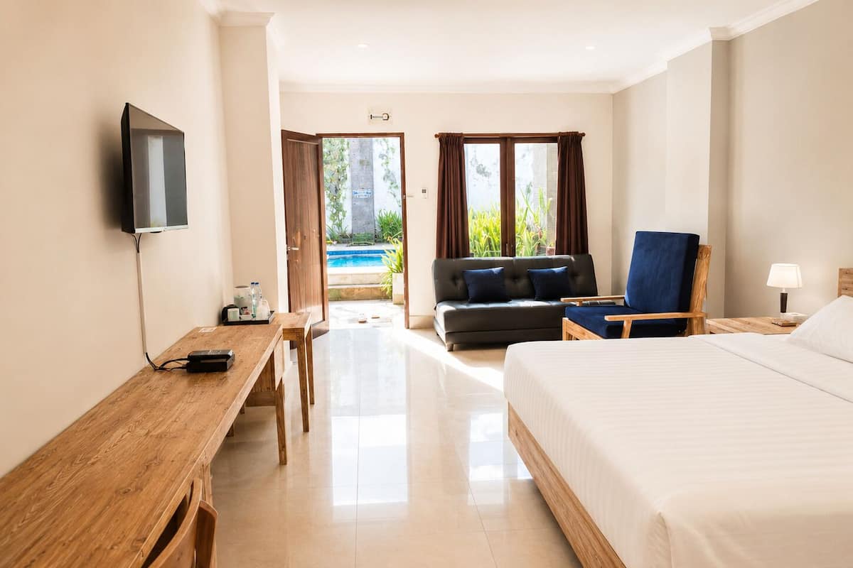 Une chambre d’hôtel équipée d’un lit, d’un bureau, d’une chaise, d’une télévision et offrant une vue sur une piscine.