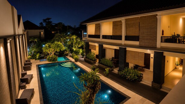 A swimming pool with surrounding lounge areas and a building with multiple balconies.